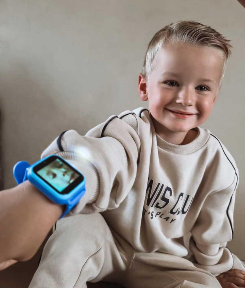 Jongen laat zijn blauwe TinyPlay smartwatch om zijn pols zien
